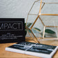 a black greeting card with the word "impact" in a box at the top followed by the definition of the word impact. The inside of the card says "thank you for making such an impact in my life"